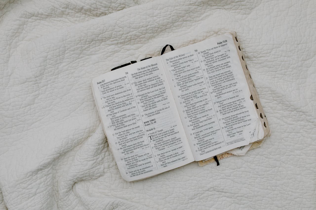 An overhead shot of an open Bible resting on a soft quilt, evoking a peaceful and contemplative atmosphere.